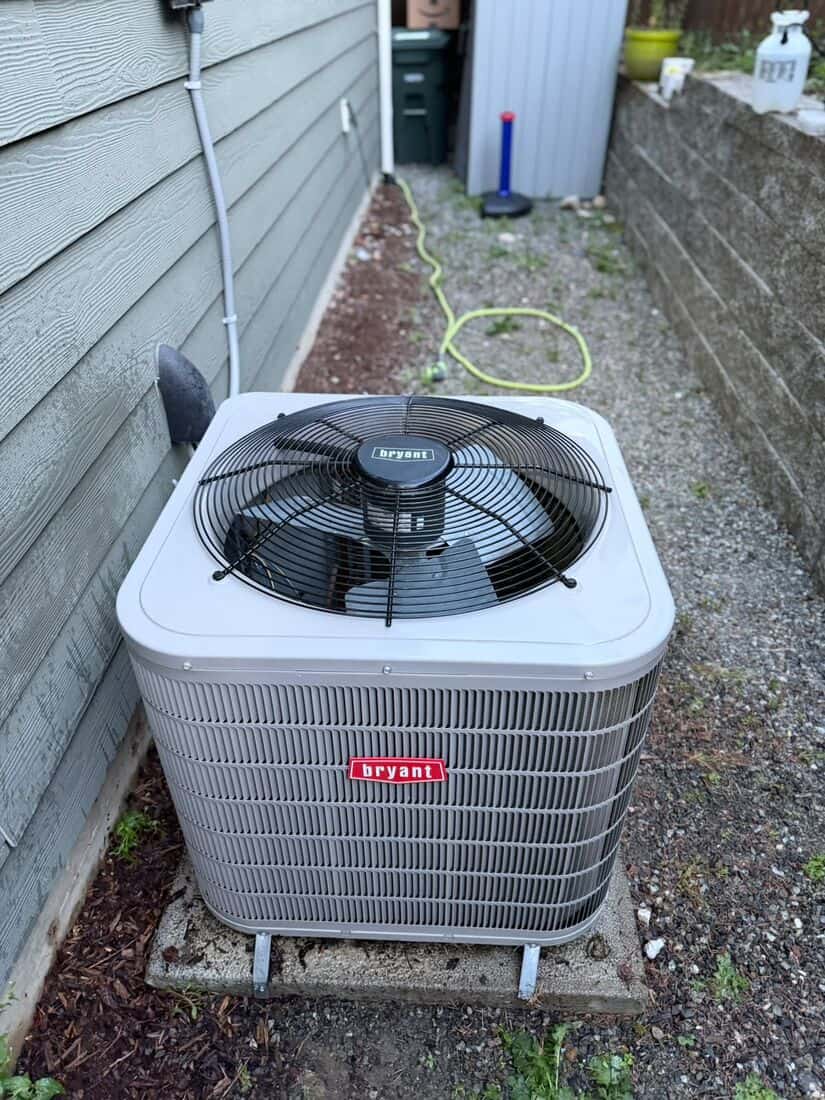 Bryant outdoor condenser unit set in a narrow side yard next to green lap siding